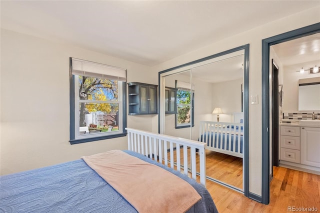 bedroom with light wood-style floors, a closet, and a sink