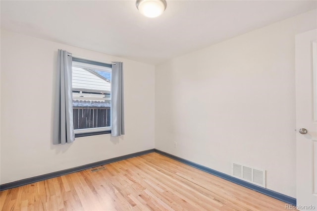 spare room with light wood-style floors, visible vents, and baseboards