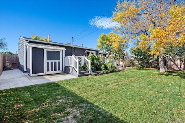 rear view of property featuring a patio, a storage unit, a lawn, a fenced backyard, and an outdoor structure