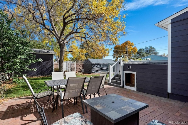 view of patio / terrace with an outbuilding, outdoor dining area, fence, and a shed