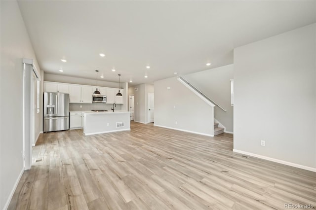 6225 N Nepal Ct, Aurora, CO 80019 - unfurnished living room with baseboards, light wood-style floors, recessed lighting, stairway, and a sink