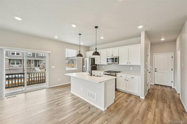 6225 N Nepal Ct, Aurora, CO 80019 - kitchen with stainless steel appliances, a sink, white cabinetry, light wood finished floors, and recessed lighting