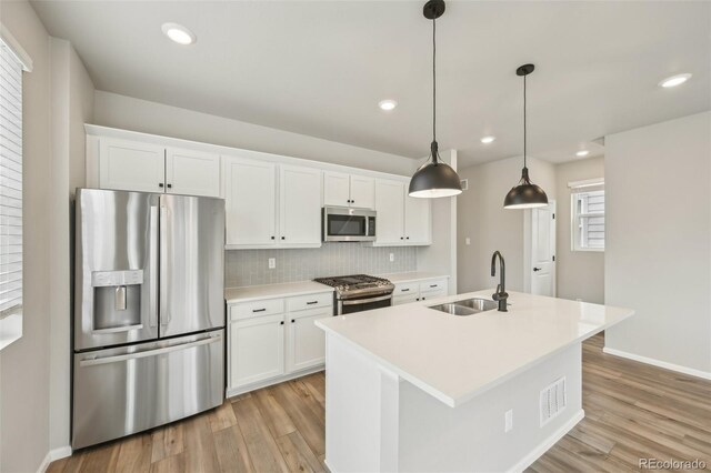 6225 N Nepal Ct, Aurora, CO 80019 - kitchen with appliances with stainless steel finishes, a sink, light wood-type flooring, white cabinetry, and recessed lighting