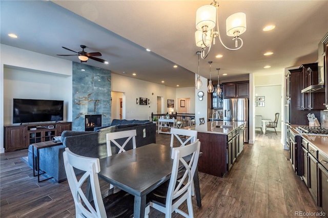 dining area with sink, a tile fireplace, dark hardwood / wood-style floors, and ceiling fan