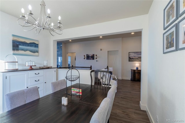 dining area with dark wood-type flooring and an inviting chandelier