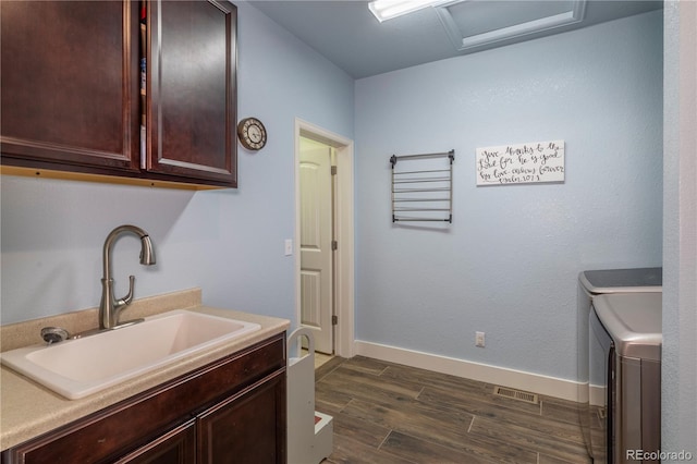 washroom featuring dark wood-type flooring, cabinets, sink, and washer and dryer