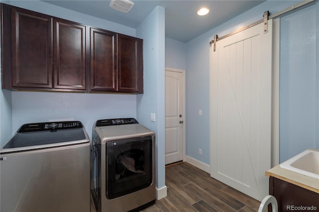 laundry room with cabinets, a barn door, dark hardwood / wood-style floors, and independent washer and dryer