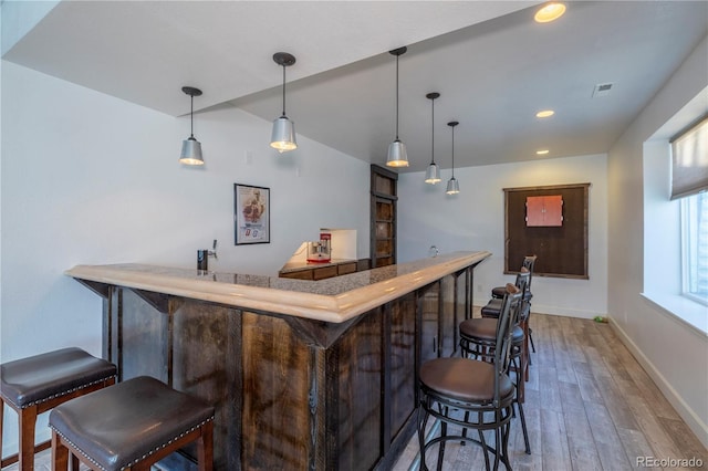 bar with lofted ceiling, wood-type flooring, and hanging light fixtures