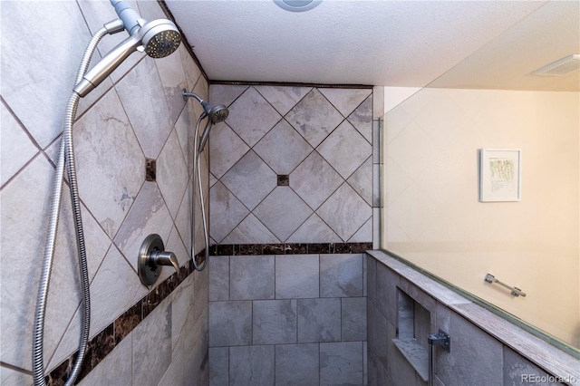 bathroom featuring a textured ceiling and tiled shower