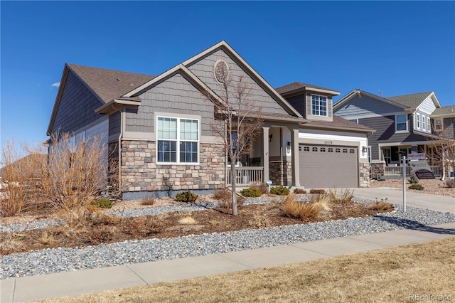 craftsman inspired home featuring a garage, stone siding, a porch, and concrete driveway