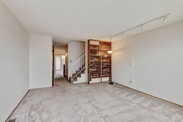 9188 W Ontario Dr, Littleton, CO 80128 - carpeted empty room with stairway, a textured ceiling, and rail lighting