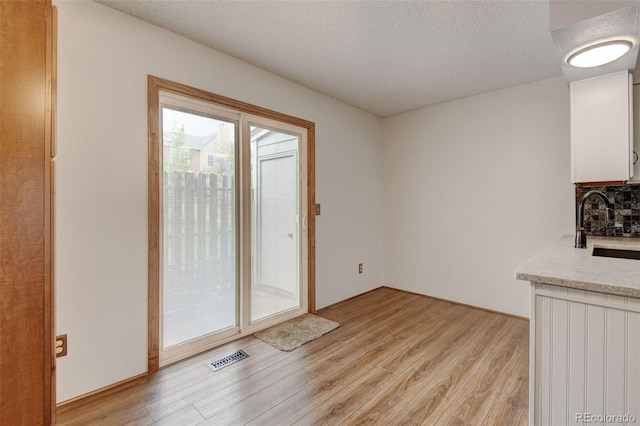 9188 W Ontario Dr, Littleton, CO 80128 - unfurnished dining area featuring light wood-type flooring, a textured ceiling, and a sink
