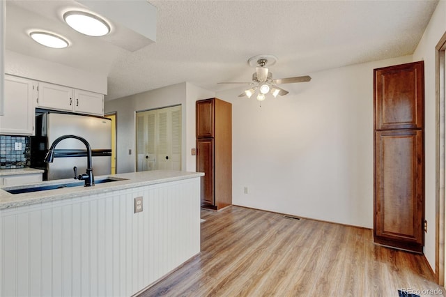9188 W Ontario Dr, Littleton, CO 80128 - kitchen featuring a sink, light countertops, light wood-style floors, ceiling fan, and decorative backsplash