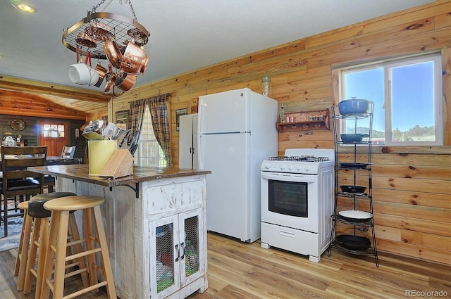 1106 Hull Ave, Westcliffe, CO 81252 - kitchen with white appliances, wood walls, light wood-type flooring, and dark countertops