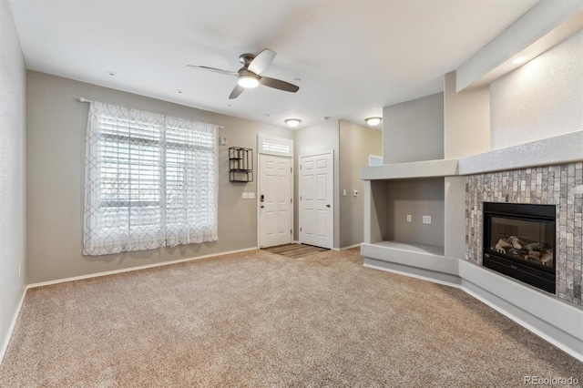 unfurnished living room with baseboards, carpet, a ceiling fan, and a tiled fireplace