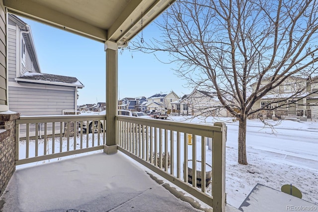 snow covered back of property featuring covered porch and a residential view