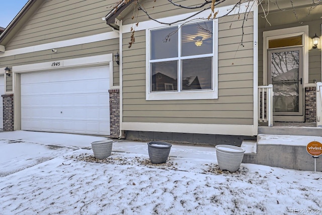 snow covered property with a garage