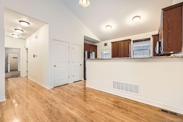 kitchen with stainless steel appliances, visible vents, light wood-style flooring, and light stone countertops