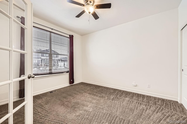 empty room with french doors, dark colored carpet, visible vents, a ceiling fan, and baseboards