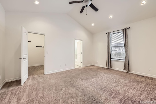 unfurnished bedroom with light carpet, baseboards, visible vents, lofted ceiling, and a walk in closet