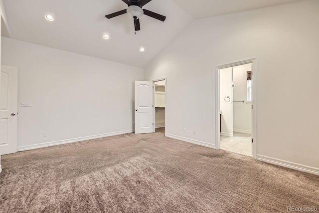 unfurnished bedroom featuring a walk in closet, recessed lighting, light colored carpet, vaulted ceiling, and baseboards