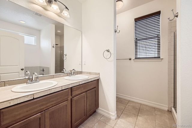 full bathroom with a shower with door, tile patterned flooring, visible vents, and a sink