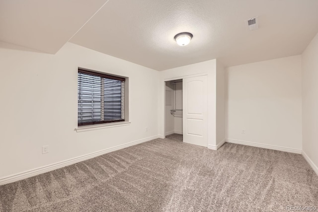 unfurnished bedroom featuring carpet, a closet, baseboards, and a textured ceiling