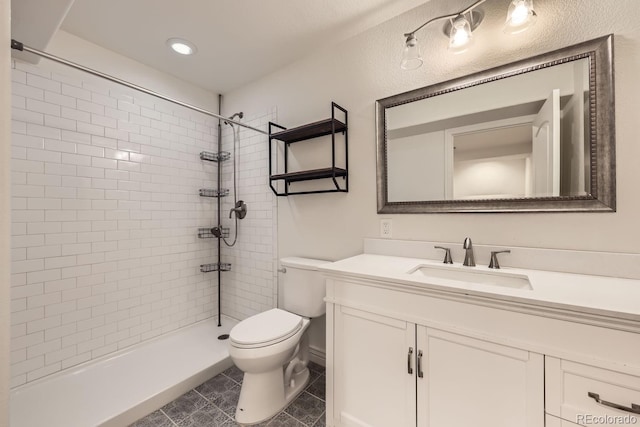 full bathroom featuring tile patterned flooring, a tile shower, vanity, and toilet