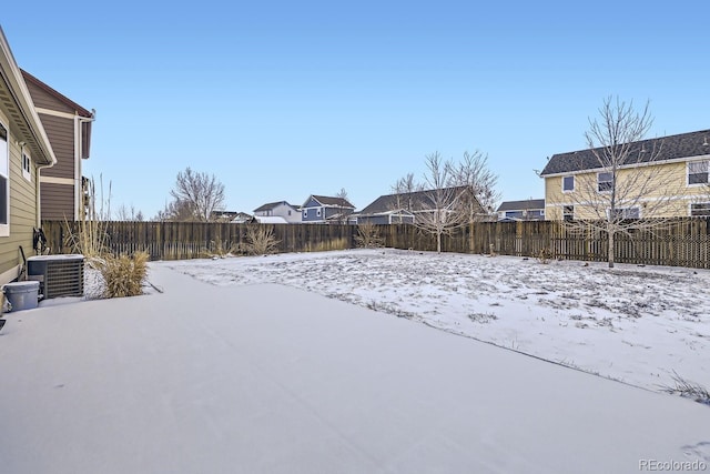 yard layered in snow featuring a fenced backyard and central AC