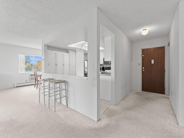 entrance foyer featuring light colored carpet, a textured ceiling, and a baseboard radiator