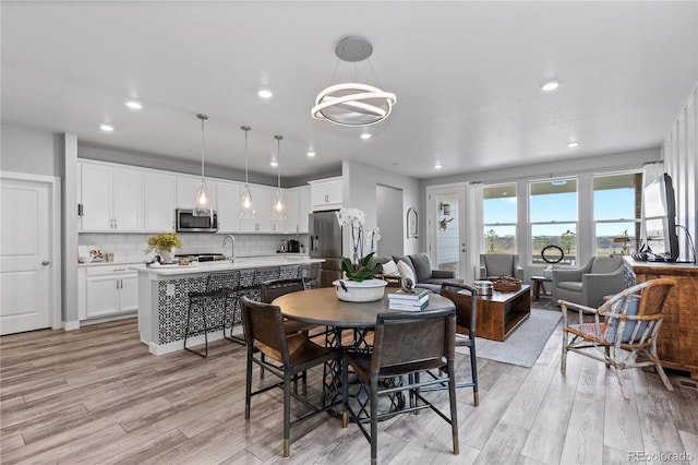 dining space with recessed lighting, light wood-style flooring, and an inviting chandelier