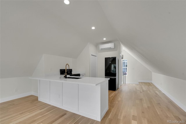 671 Elati St, Denver, CO 80204 - additional living space featuring a wall unit AC, vaulted ceiling, a sink, light wood finished floors, and baseboards