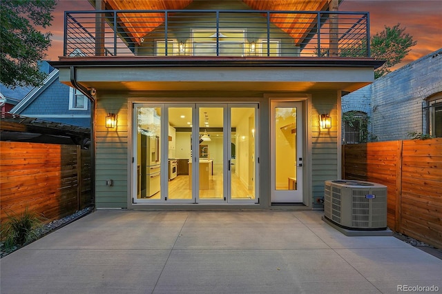 671 Elati St, Denver, CO 80204 - exterior entry at dusk featuring a balcony, cooling unit, and a patio