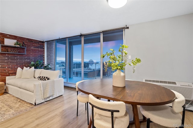 dining area with baseboard heating, brick wall, floor to ceiling windows, and light wood finished floors