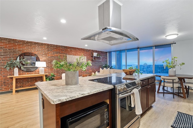 kitchen featuring black microwave, electric range, light wood-type flooring, a center island, and island exhaust hood