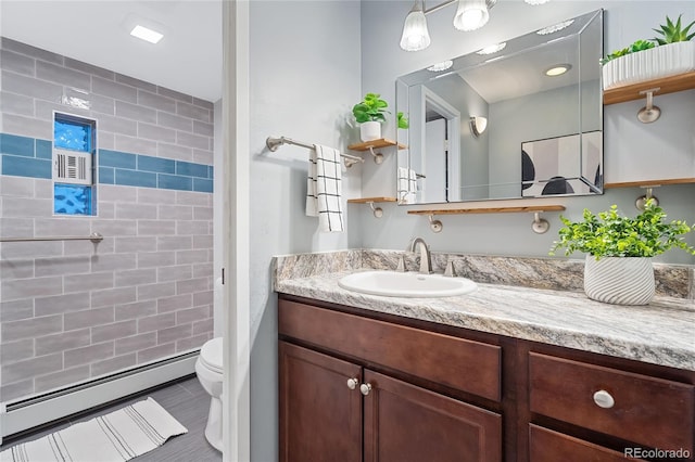 full bathroom with a baseboard heating unit, a tile shower, vanity, and toilet