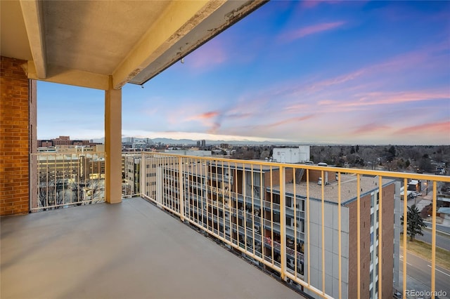 balcony at dusk featuring a view of city