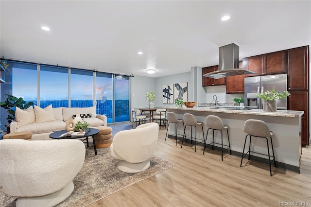 living area with a wall of windows, recessed lighting, and light wood finished floors