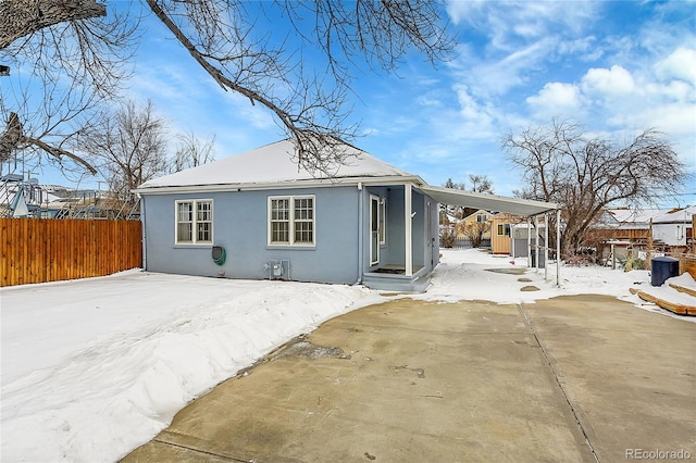 snow covered house featuring a carport