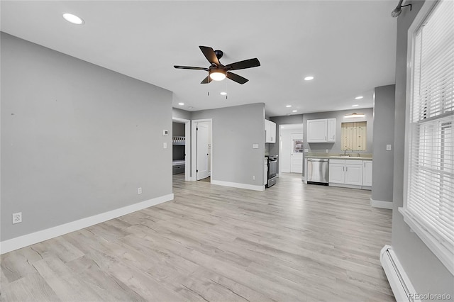 unfurnished living room featuring ceiling fan, light wood-type flooring, sink, and baseboard heating