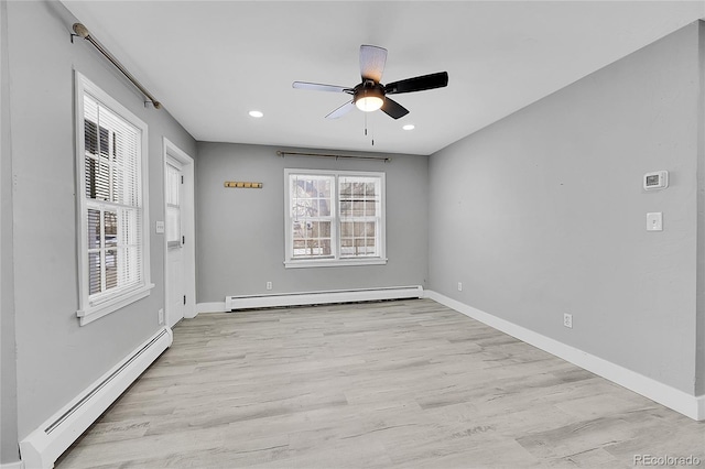 spare room featuring light wood-type flooring, a wealth of natural light, and baseboard heating