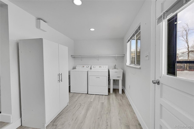 laundry room with washer and dryer, sink, and light hardwood / wood-style floors