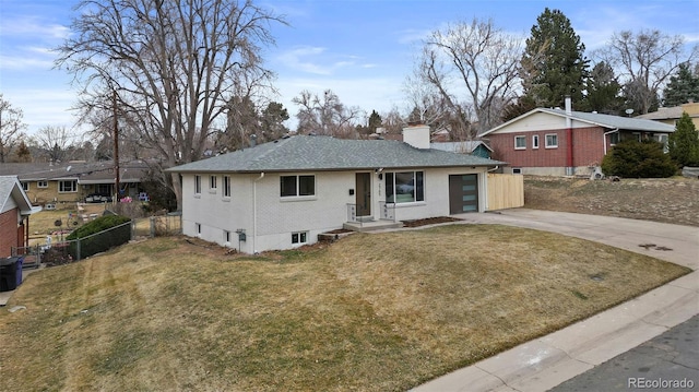 ranch-style home featuring a front lawn, driveway, fence, brick siding, and a chimney