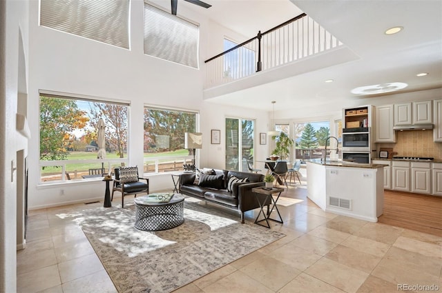 living room with a towering ceiling, sink, and light tile patterned floors