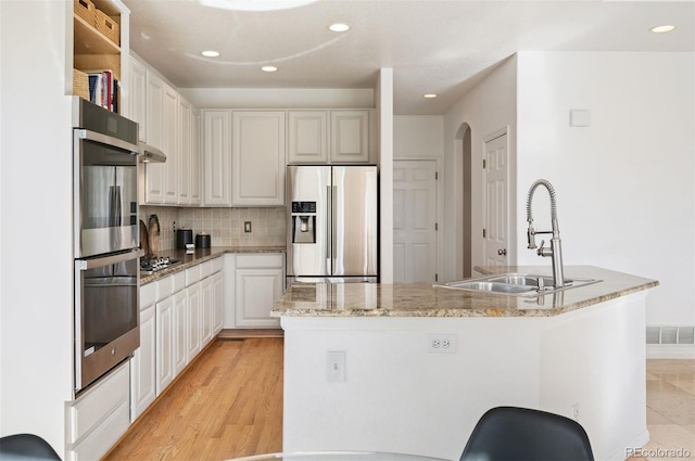 kitchen featuring a sink, stainless steel appliances, arched walkways, decorative backsplash, and recessed lighting