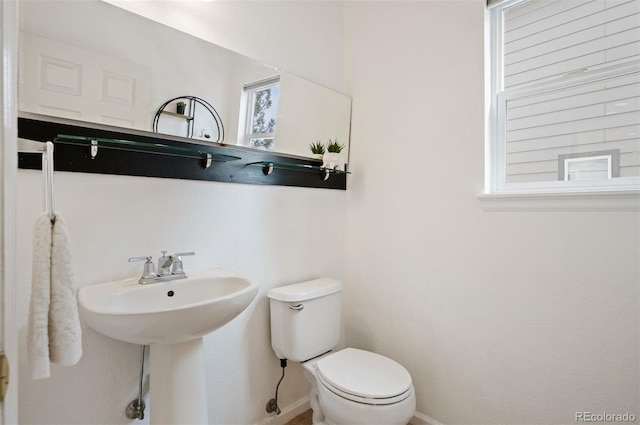 half bath featuring toilet and baseboards