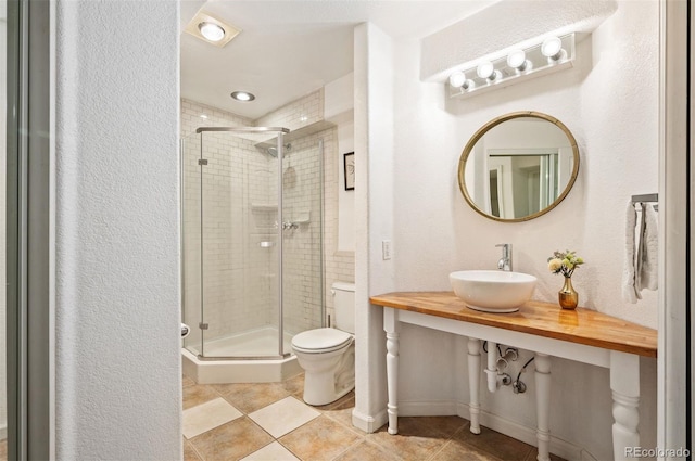 bathroom with sink, a shower with shower door, toilet, and tile patterned flooring