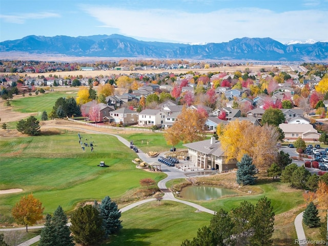 drone / aerial view featuring golf course view, a residential view, and a water and mountain view