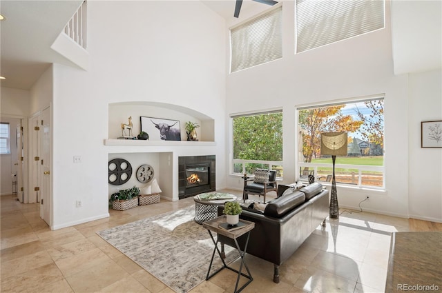 living room featuring a fireplace, a towering ceiling, and baseboards