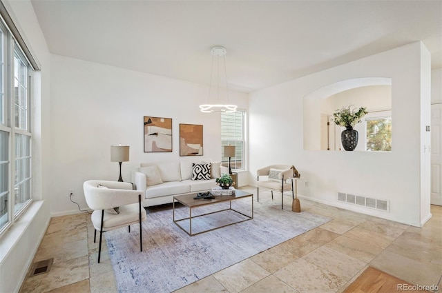 living room with visible vents, a healthy amount of sunlight, and a notable chandelier